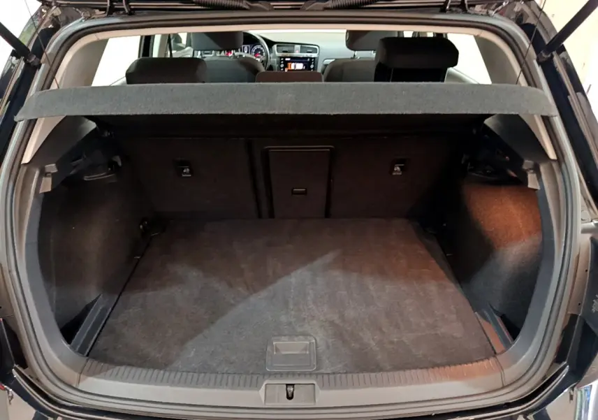 Coffre ouvert d'une Volkswagen Golf noire 2018, vue arrière montrant l'espace de chargement et la tablette cache-bagages.