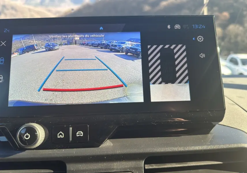 Écran tactile intérieur montrant la caméra de recul avec vue arrière et aide au stationnement du Peugeot Rifter noir perla nera.