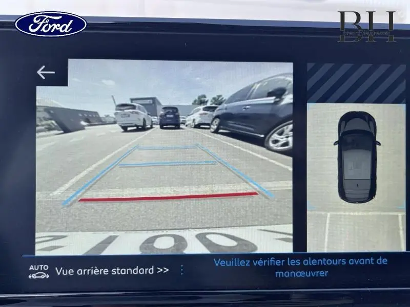 Image d'écran de caméra de recul montrant une vue arrière standard d'un parking avec plusieurs voitures garées.