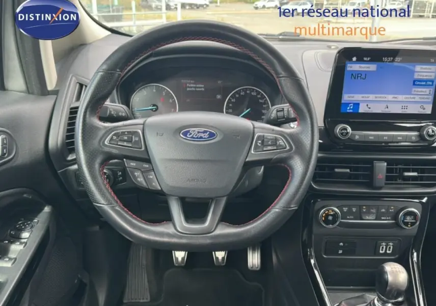 Vue intérieure centrée sur le volant Ford avec commandes intégrées et écran tactile du tableau de bord.