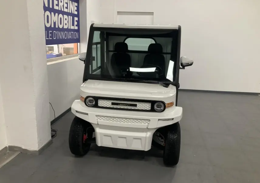 Vue frontale d'un véhicule électrique blanc Liberty L7E H2 160 avec kit ridelles et phares LED ronds.