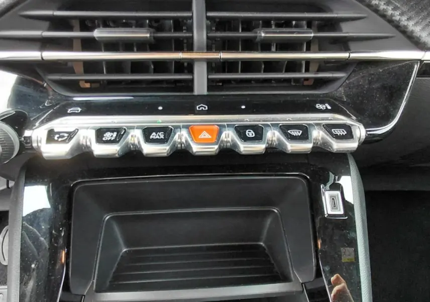 Vue rapprochée de la console centrale du Peugeot 2008 Hybrid 145 Style 2025 noir, avec boutons chromés et bouton orange d’alerte.