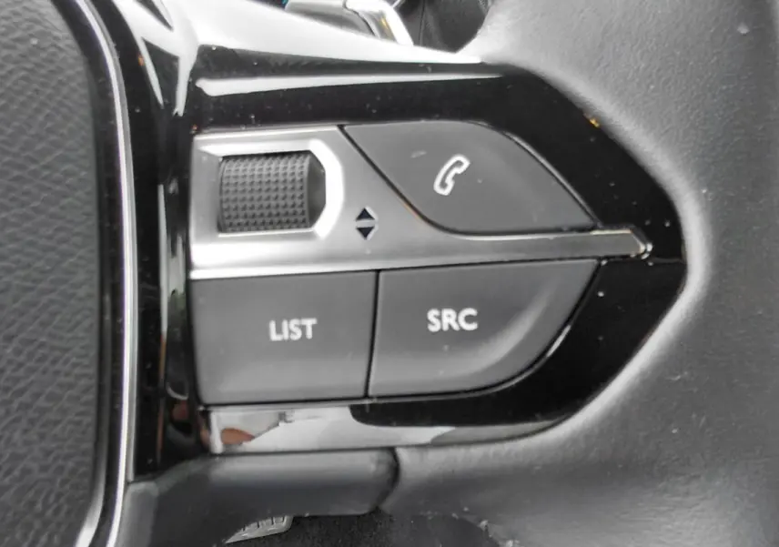 Détail du côté gauche du volant noir du Peugeot 2008 Hybrid 145 e-DCS6 Style 2025 avec commandes audio intégrées.