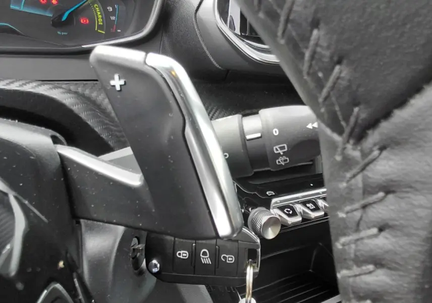 Gros plan sur la palette de changement de vitesse + au volant cuir noir du Peugeot 2008 Hybrid 145 e-DCS6 Style 2025.