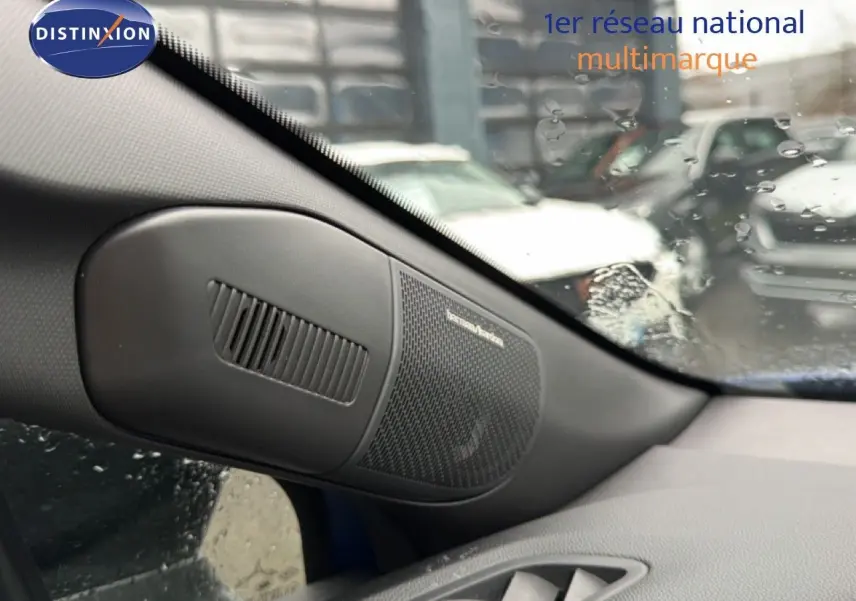 Détail de l'enceinte Harman Kardon côté gauche dans l'habitacle du Renault Captur bleu Iron Metal 2025.
