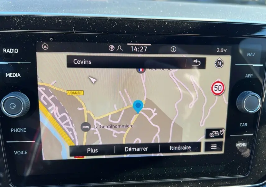 Écran tactile du système de navigation du Volkswagen T-Cross blanc, affichant une carte avec itinéraire et commandes latérales.