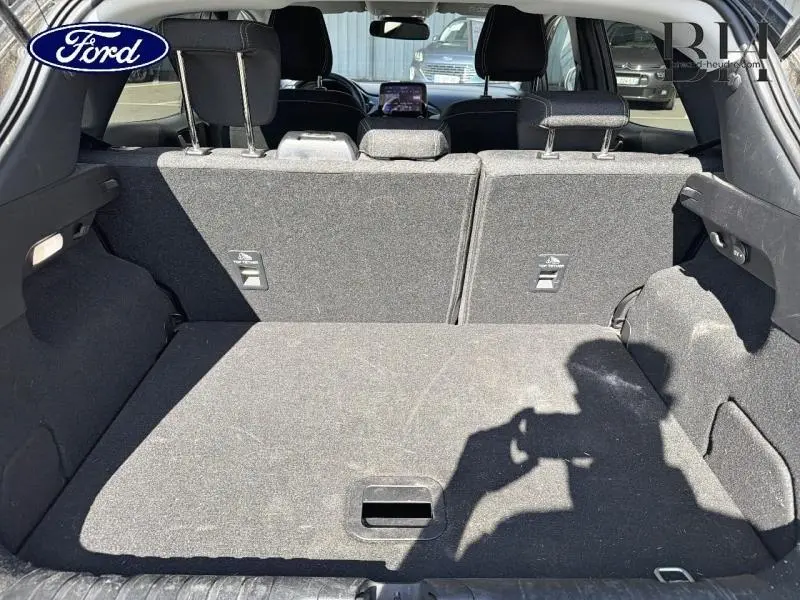 Vue depuis le coffre du Ford Puma 2024 gris métallisé, montrant l’espace de chargement et les dossiers arrière en tissu noir.