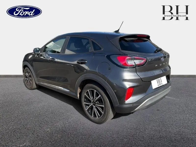 Vue 3/4 arrière droite d'une Ford Puma 2024 gris métallisé avec vitres arrière surteintées et jantes noires.