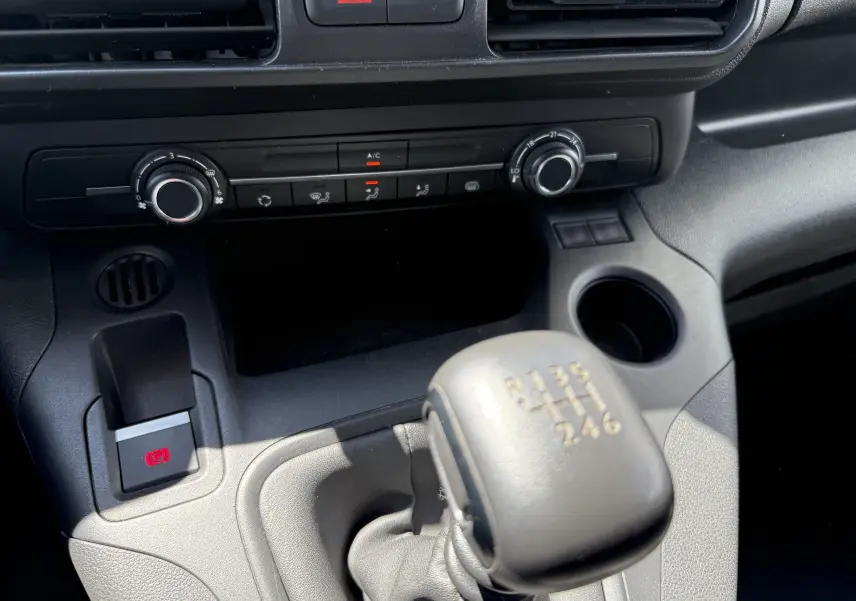 Gros plan sur la commande de boîte manuelle et la console centrale noire du Citroën Berlingo XL blanc banquise 2022.