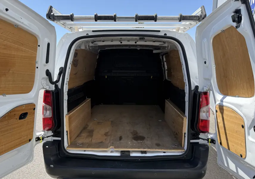Vue arrière ouverte d’un Citroën Berlingo XL blanc banquise, montrant l’espace de chargement avec protection en bois.