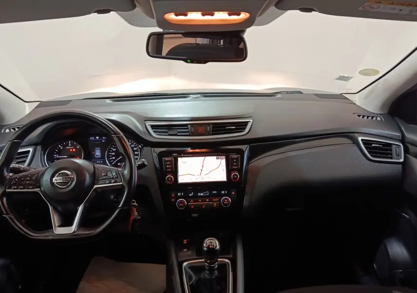 Tableau de bord et volant noir du Nissan Qashqai 2019, avec écran tactile de navigation et levier de vitesses manuel.