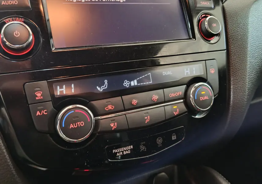 Gros plan sur la console centrale noire du Nissan Qashqai 2019, montrant les commandes de climatisation digitale bi-zone.