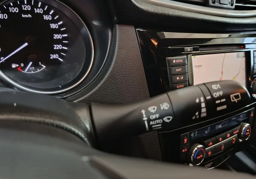Détail intérieur du tableau de bord du Nissan Qashqai 2019 montrant la commande d'essuie-glace et l'écran tactile de navigation.