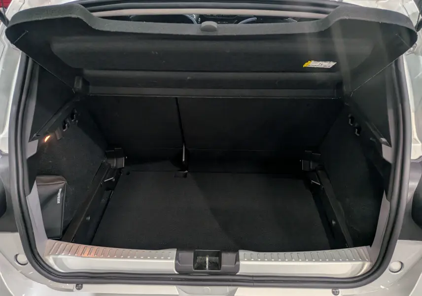 Coffre ouvert vu de l'arrière d'une Dacia Sandero Stepway gris Moonstone, montrant un espace de rangement vide et propre.