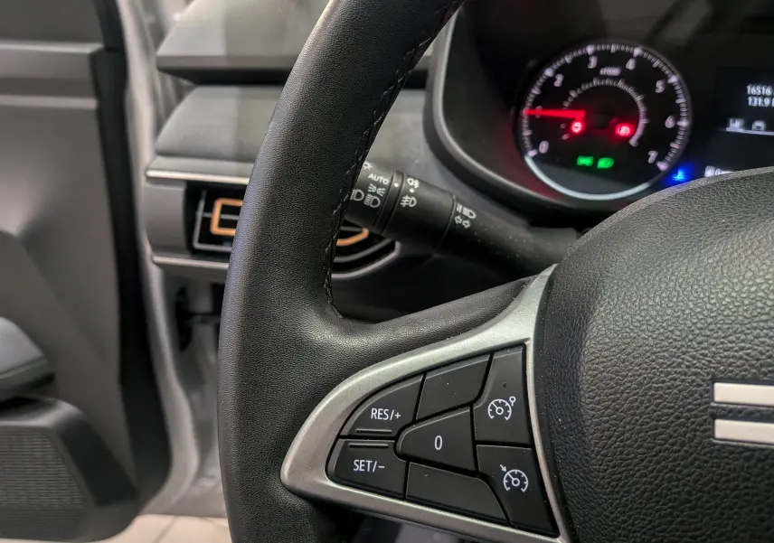 Gros plan sur le volant noir avec commandes de régulateur de vitesse du Dacia Sandero Stepway 2023, intérieur gris.