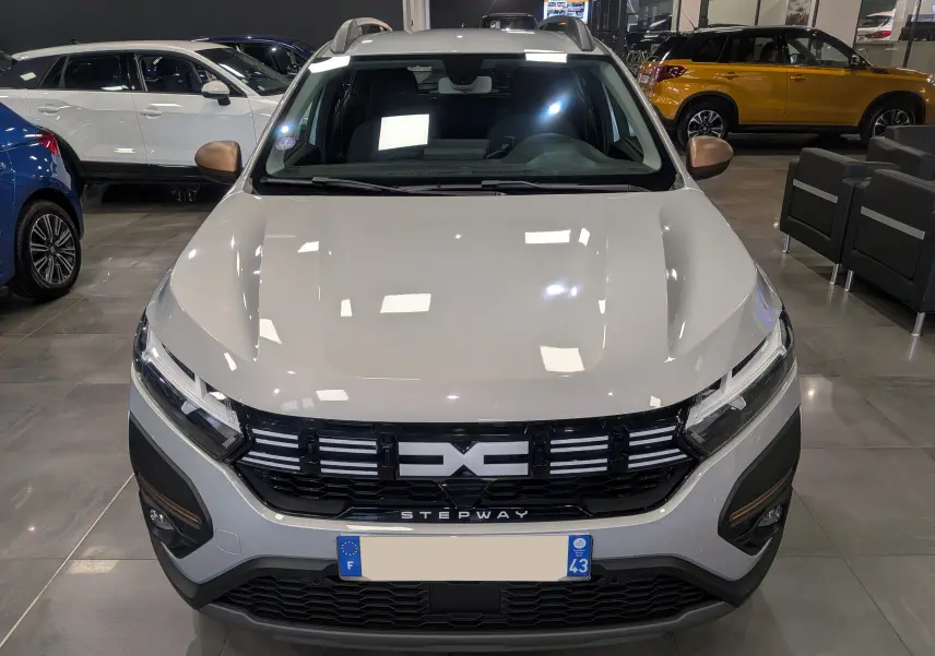 Vue avant d'une Dacia Sandero Stepway 2023 gris Moonstone avec calandre noire et détails bronze sur les rétroviseurs.