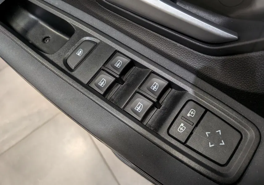 Gros plan sur les commandes des vitres électriques et réglages des rétroviseurs côté conducteur du Dacia Sandero Stepway gris Moonstone 2023.