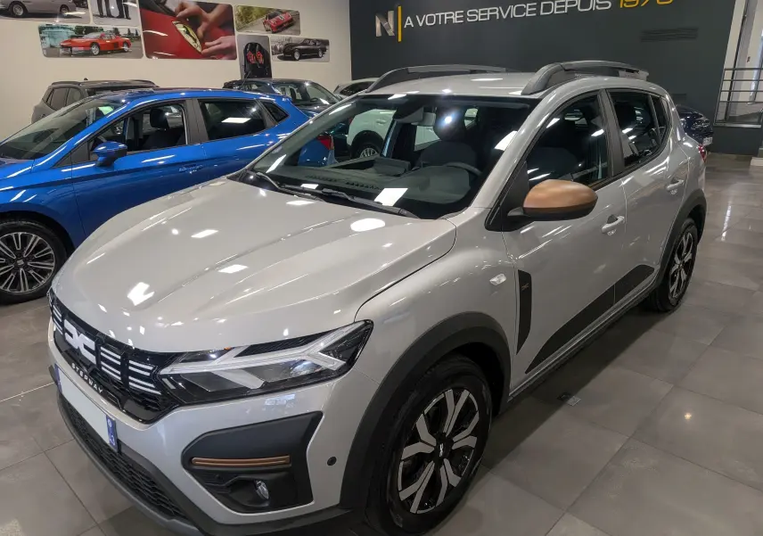 Dacia Sandero Stepway gris Moonstone en 3/4 avant droit, avec coques de rétroviseurs bronze et jantes bi-ton.