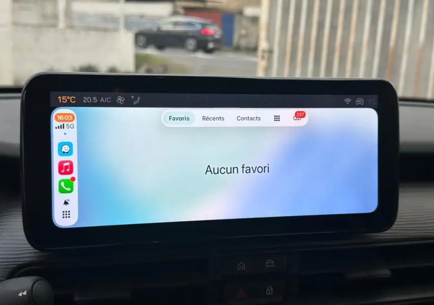 Écran tactile intérieur du Jeep Avenger 2024 affichant un menu de favoris, avec vue partielle du tableau de bord noir.