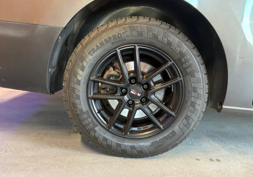 Gros plan sur la roue arrière droite du Citroën Jumpy gris, mettant en valeur la jante noire à multiples branches.