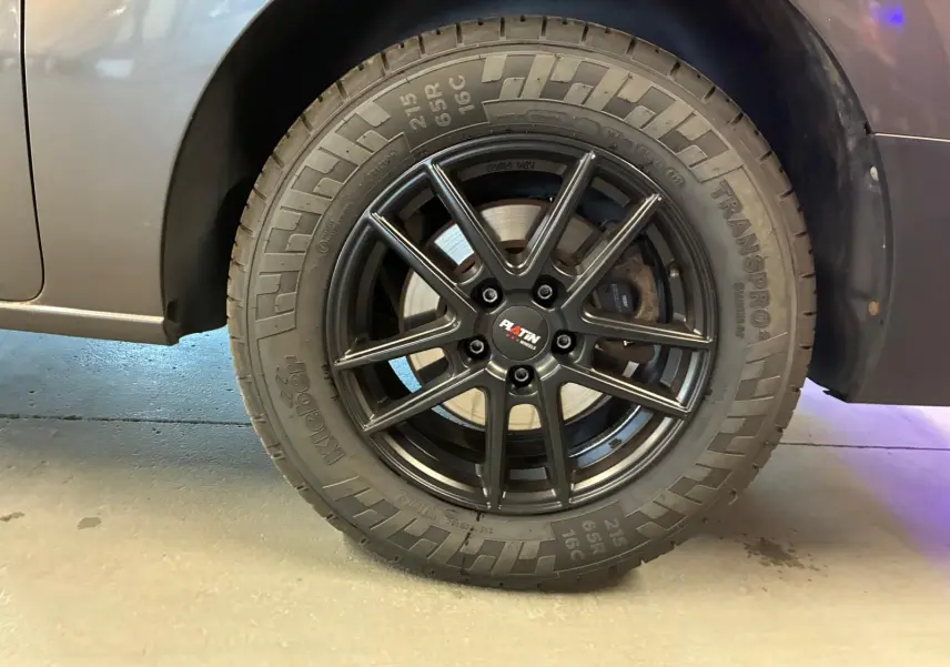 Gros plan sur la roue arrière droite du Citroën Jumpy gris, avec jante noire à dix branches et pneu tout-terrain.