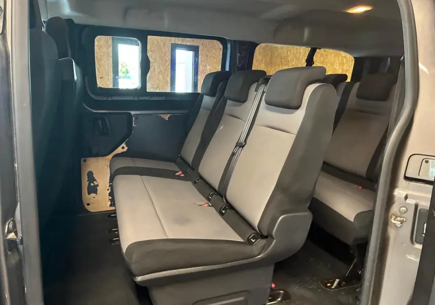 Vue intérieure côté droit du Citroën Jumpy XL Spacetourer gris, montrant les sièges tissu 9 places et la porte coulissante ouverte.
