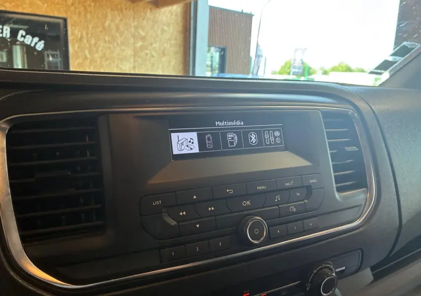 Vue intérieure du tableau de bord du Citroën Jumpy gris, avec écran multimédia et commandes centrales visibles.