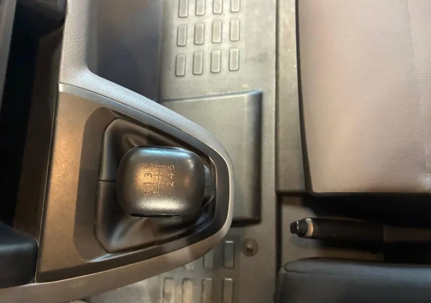 Gros plan sur le levier de vitesses manuel noir du Citroën Jumpy gris, avec frein à main et siège tissu visibles.