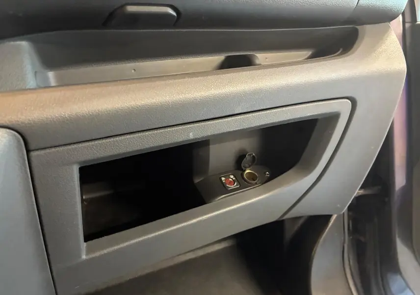 Gros plan sur le rangement côté passager du Citroën Jumpy gris, mettant en valeur une prise allume-cigare ouverte.