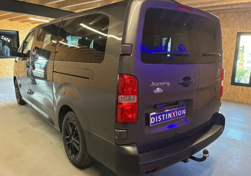 Vue 3/4 arrière droite d’un Citroën Jumpy XL Spacetourer gris, avec hayon fermé et attelage visible en intérieur lumineux.