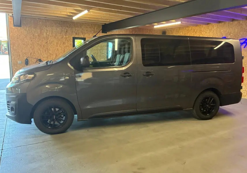 Vue de profil côté gauche d’un Citroën Jumpy XL Spacetourer gris avec vitres arrière teintées et jantes noires.