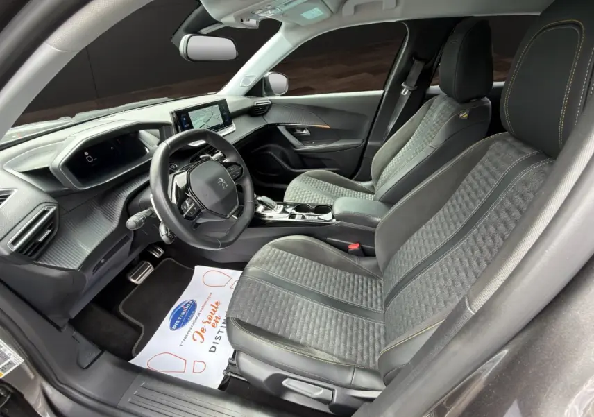 Vue intérieure côté conducteur de la Peugeot 2008 gris foncé, avec sièges tissu et cuir, volant multifonction et écran tactile.