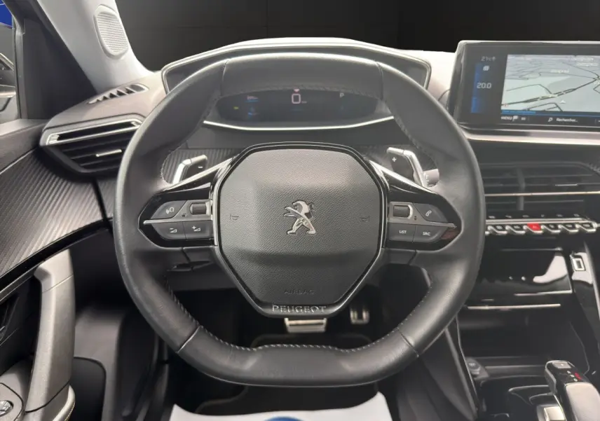 Vue centrée sur le volant cuir noir du Peugeot 2008 2022 avec tableau de bord digital et écran tactile de navigation.