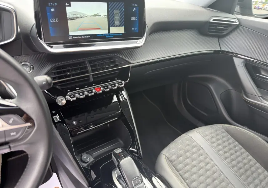 Vue intérieure côté passager du tableau de bord et console centrale noire brillante du Peugeot 2008 gris foncé 2022.
