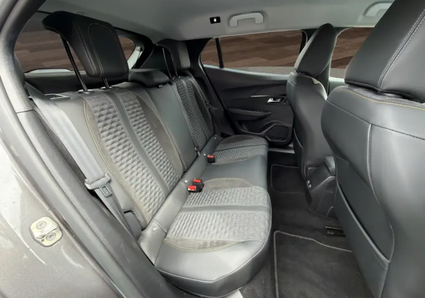 Vue intérieure arrière côté gauche du Peugeot 2008 gris foncé, montrant les sièges en tissu et cuir avec surpiqûres jaunes.