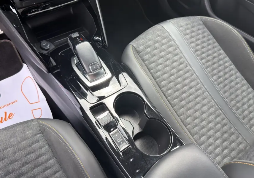 Vue rapprochée de la console centrale noire et des sièges gris avec surpiqûres jaunes du Peugeot 2008 2022.