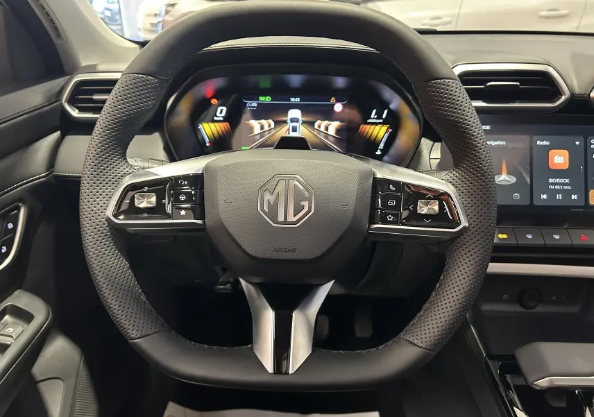 Vue frontale du volant noir perforé du MG ZS Hybrid+ 197 Luxury avec tableau de bord numérique et écran central tactile.