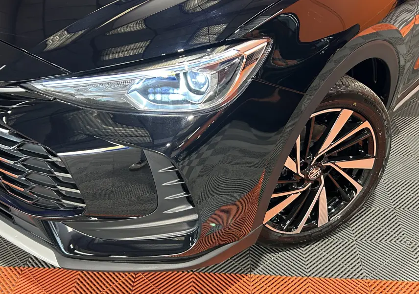 Gros plan sur l'avant droit du MG ZS Hybrid+ Pebble Black, mettant en valeur le phare LED et la jante noire et argentée.