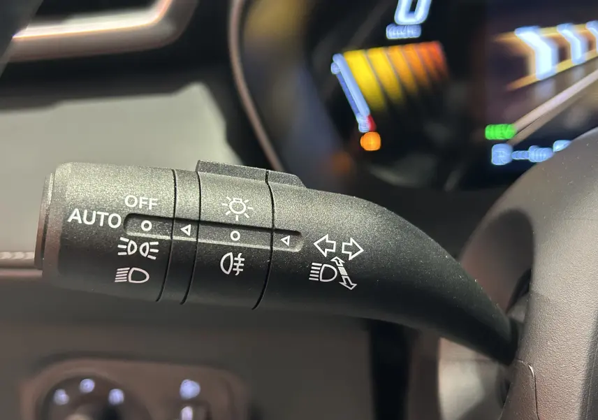 Gros plan sur la commande des feux et clignotants du MG MOTOR ZS Hybrid+ 197 Luxury, intérieur noir avec tableau de bord numérique.