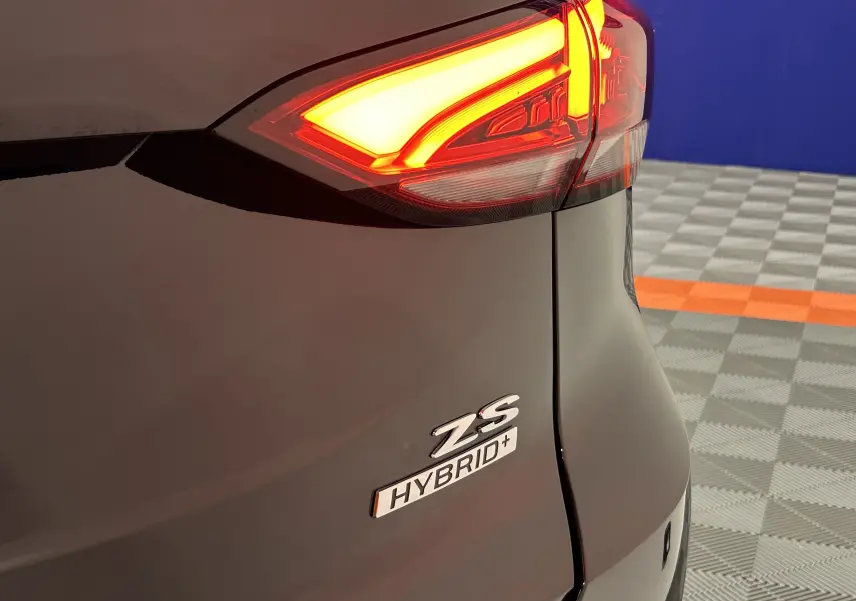 Gros plan sur l'arrière droit noir Pebble Black du MG ZS Hybrid+ avec feu arrière allumé et badges visibles.