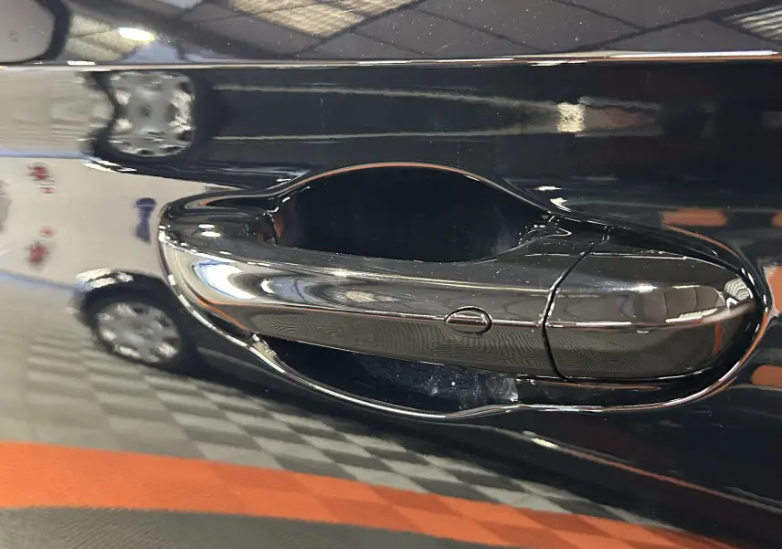 Poignée de porte chromée en gros plan sur la portière Pebble Black d'une MG MOTOR ZS Hybrid+ 197 LUXURY 2026.