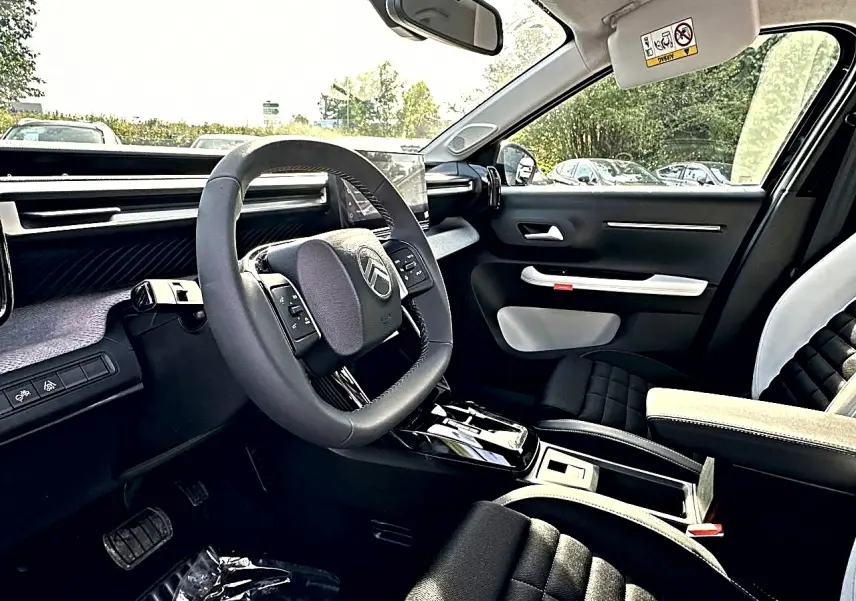 Intérieur avant droit du Citroën C3 Aircross noir 2026, volant multifonction et sièges bi-ton avec accoudoir central.
