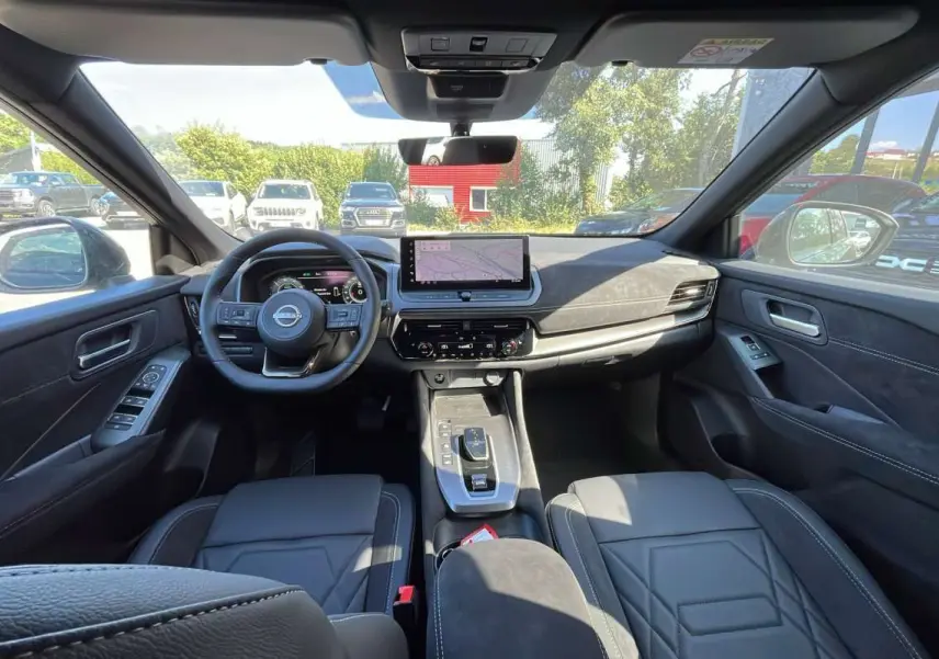 Vue intérieure avant du Nissan Qashqai E-POWER 205 N-DESIGN avec sellerie cuir alcantara noire et écran tactile central.