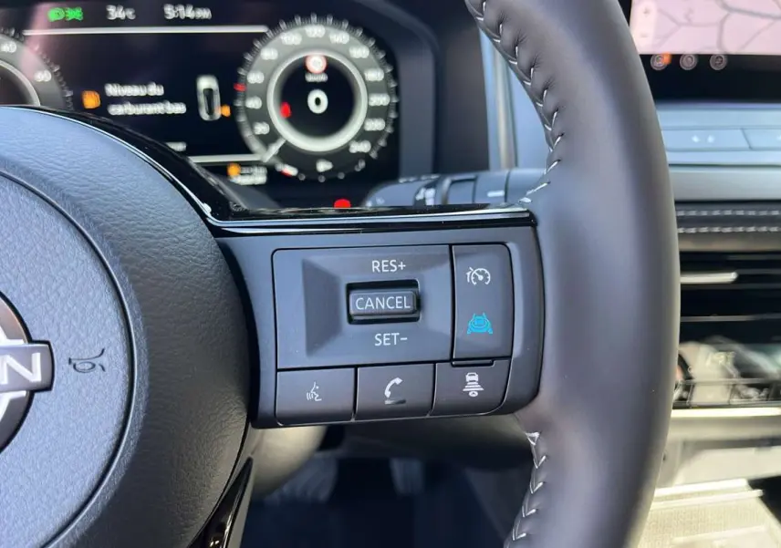 Gros plan sur le volant cuir multifonctions du Nissan Qashqai E-POWER 205 N-DESIGN avec commandes de régulateur et assistance.