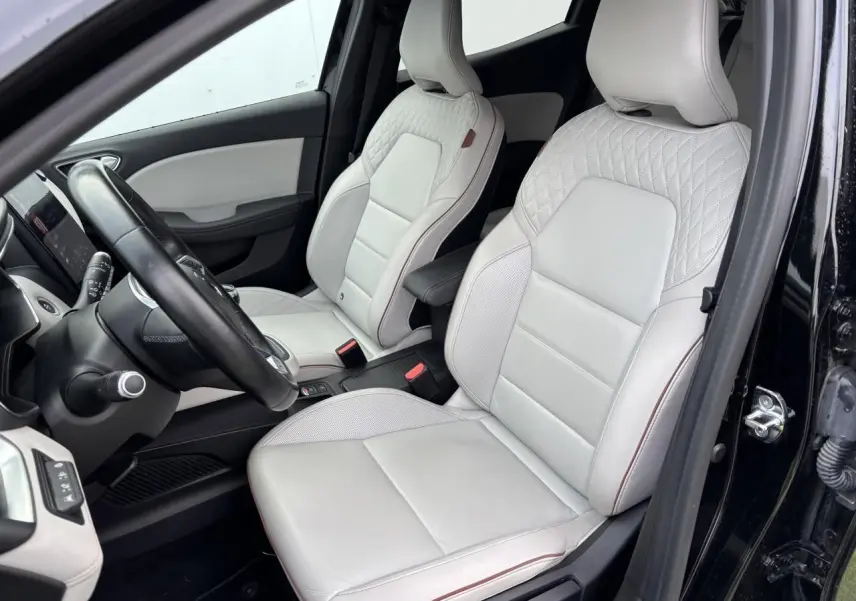 Intérieur de Renault Clio V 2020 vue côté conducteur, sièges cuir blanc avec surpiqûres et accoudoir coulissant noir.