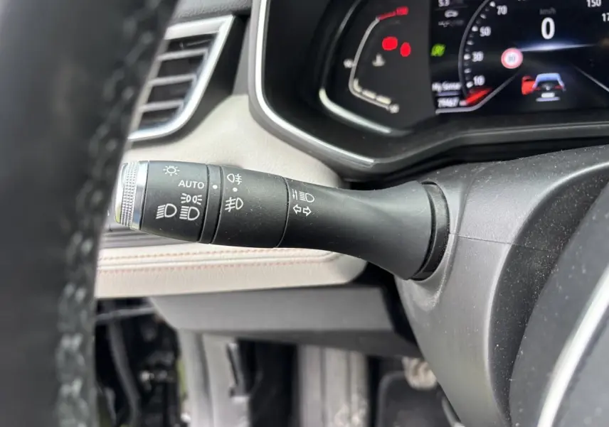 Gros plan sur la commande des feux à gauche du volant dans l'habitacle clair d'une Renault Clio Noir Étoilé 2020.