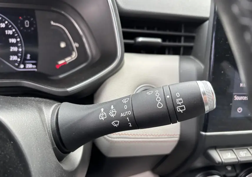 Gros plan sur la commande d’essuie-glaces à gauche du volant dans l’habitacle clair d’une Renault Clio noire étoile 2020.