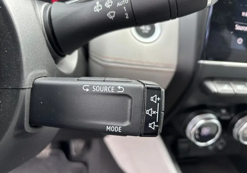 Gros plan sur la commande multimédia au volant noir de la Renault Clio V 1.0 TCE 100 Initiale Paris 2020.