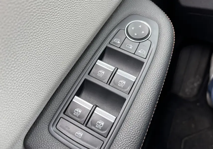 Gros plan sur les commandes des vitres électriques côté conducteur d'une Renault Clio noire étoile, finition Initiale Paris.