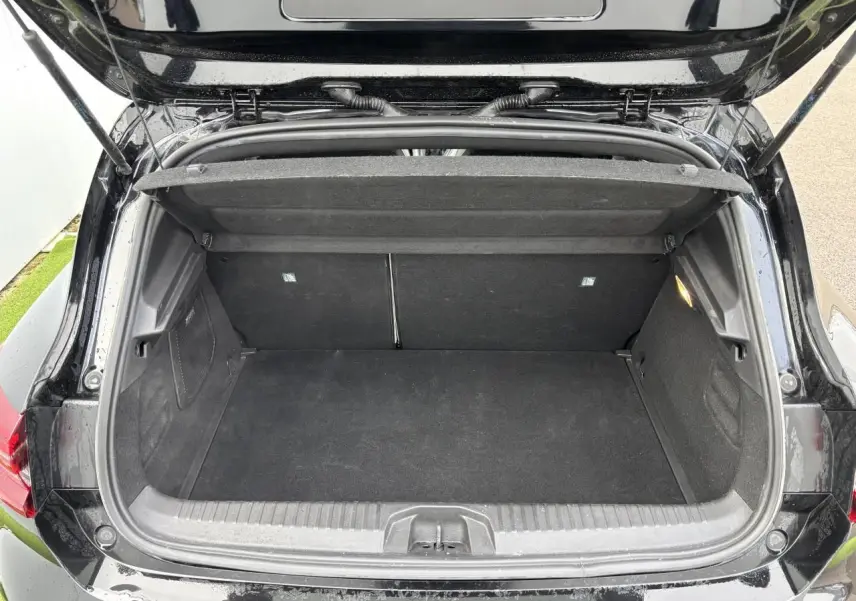 Coffre ouvert vu de l'arrière d'une Renault Clio noire étoile, montrant un espace de rangement propre et vide.